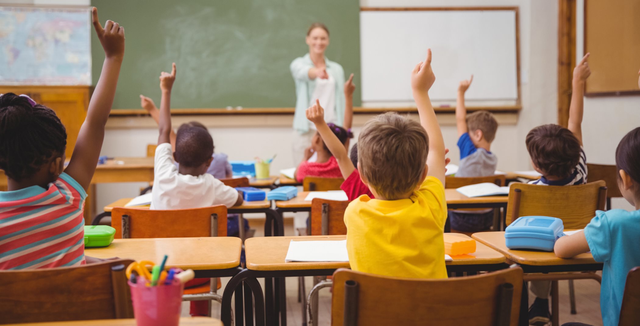 Children raising their hands for a teacher