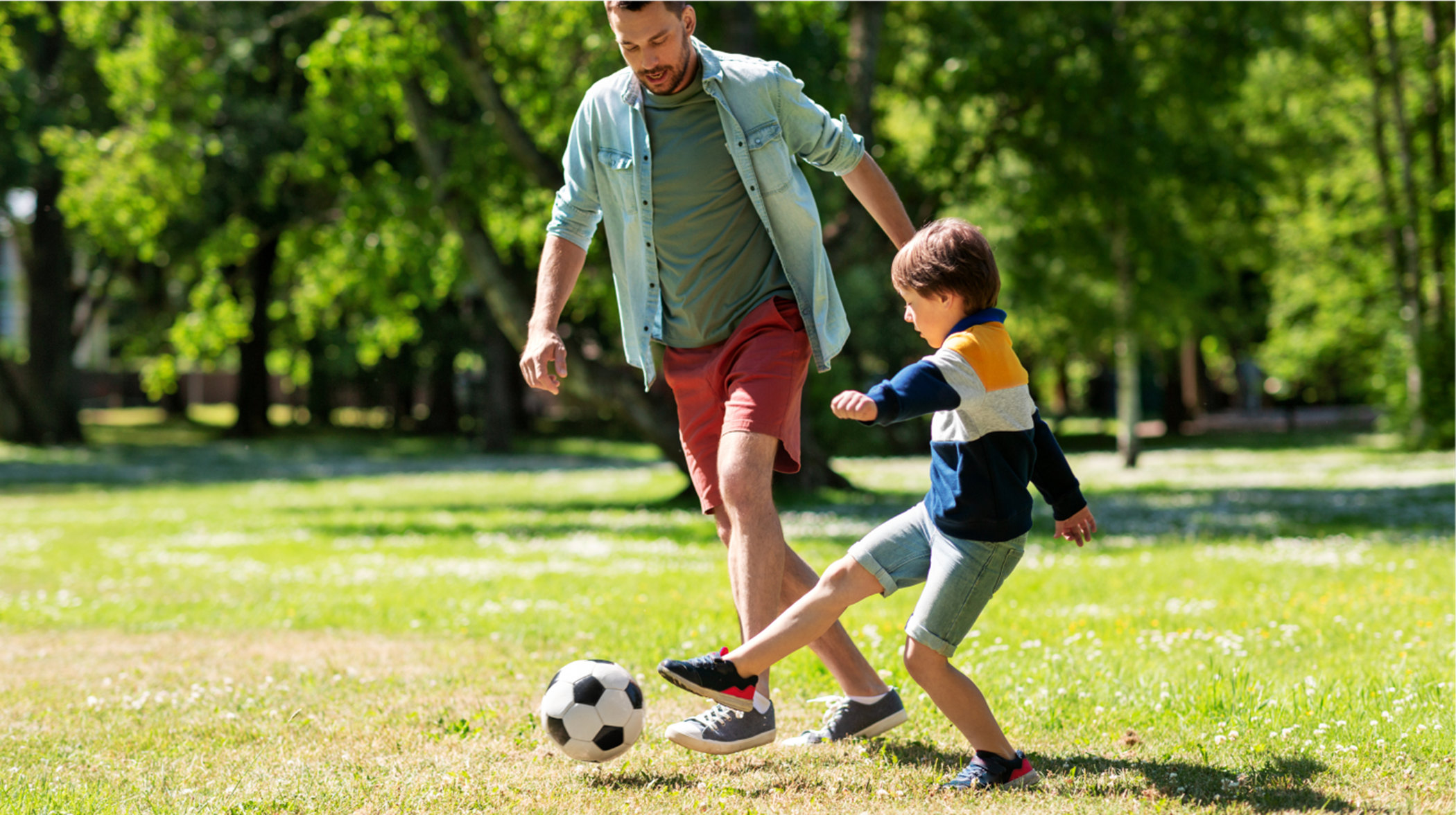 Father and son playing soccer in field