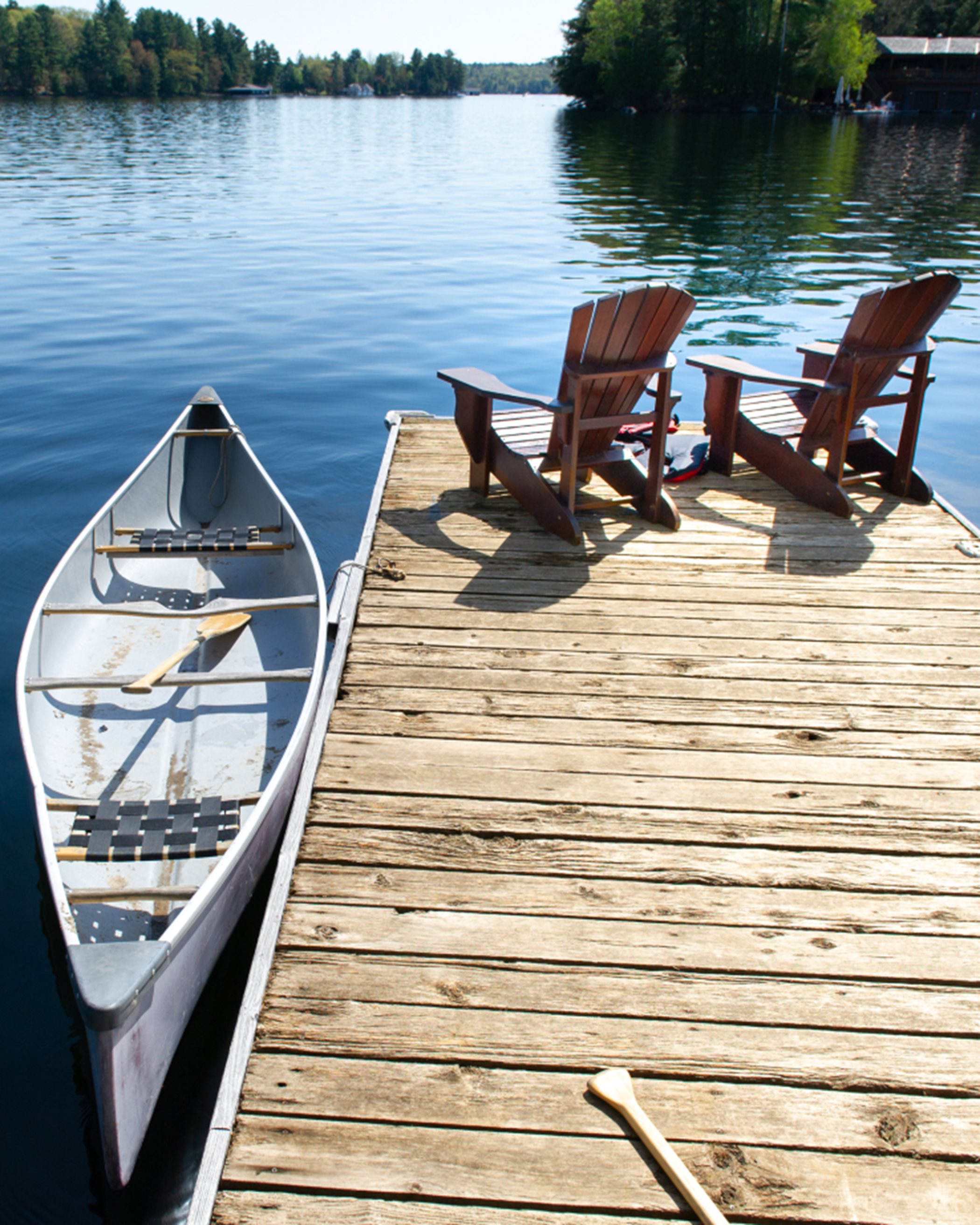 A dock with a canoe and two deck chairs