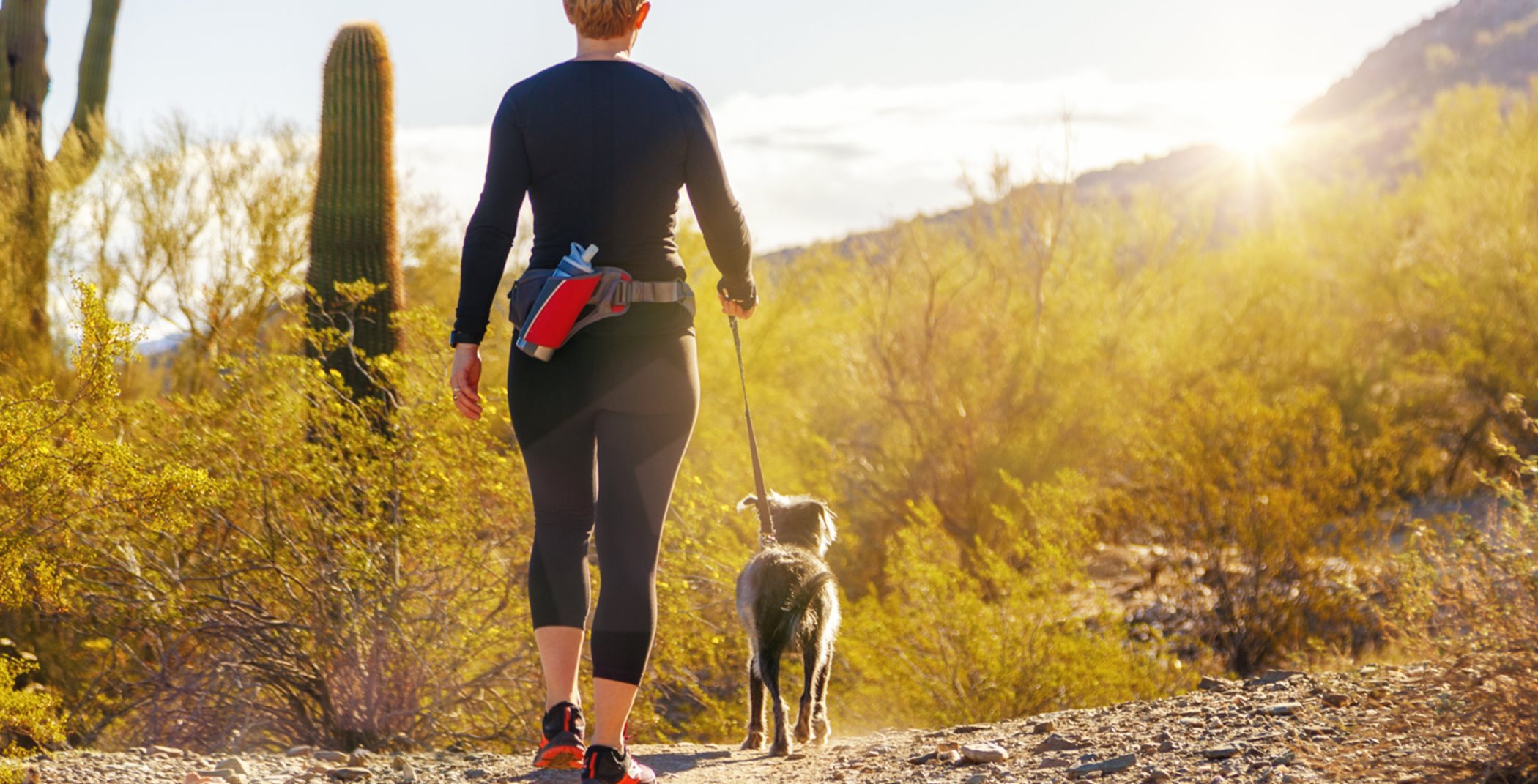 Women and dog hiking on a desert path