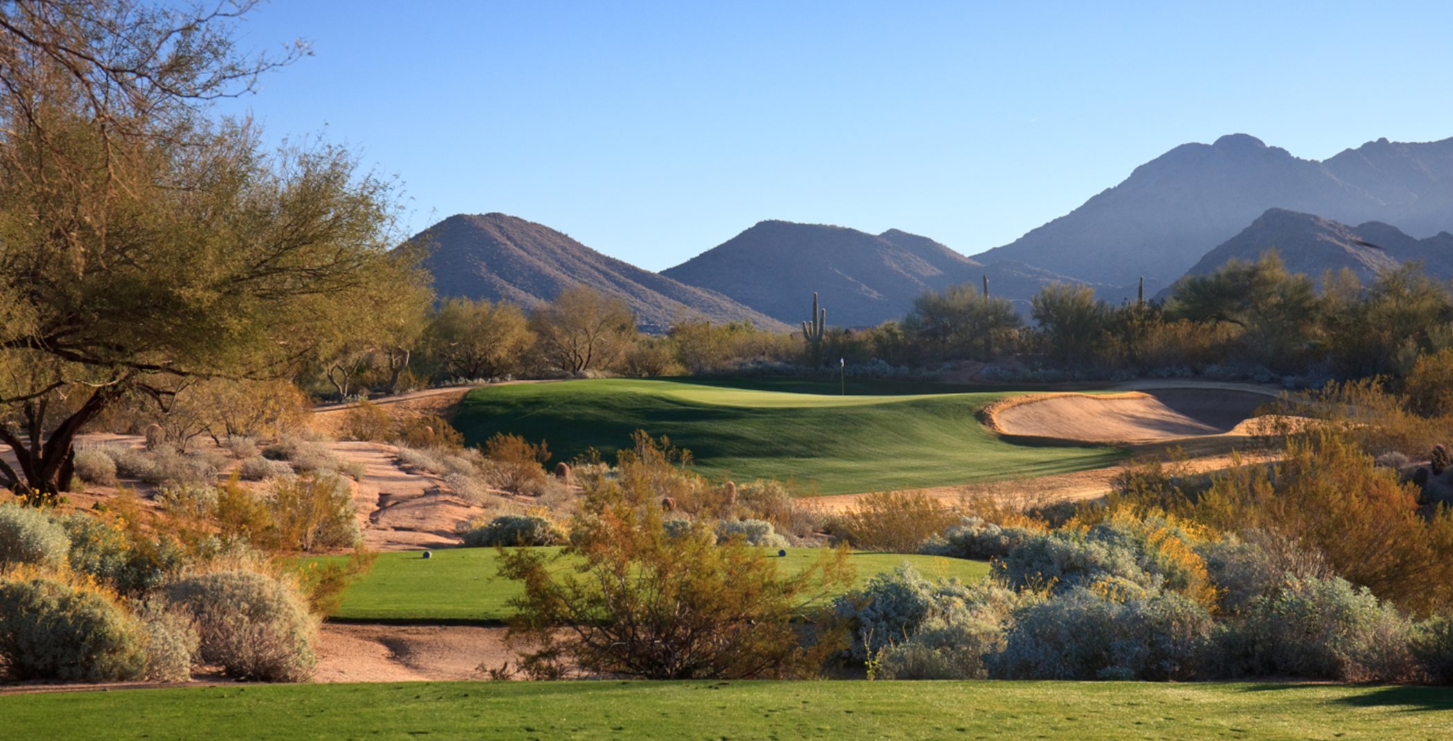 Golf course in a desert landscape with mountains in the background
