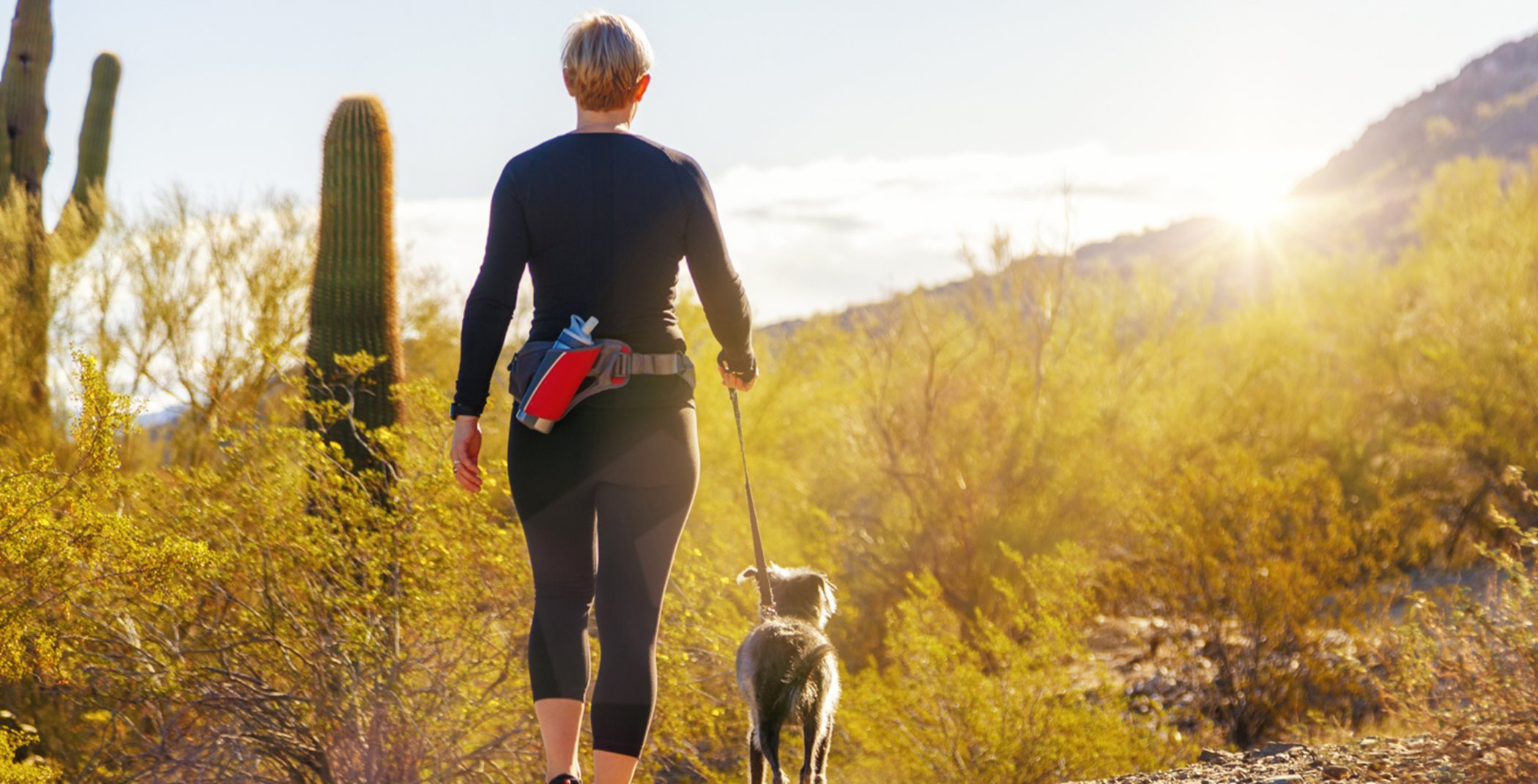 Woman hiking with dog on desert trail