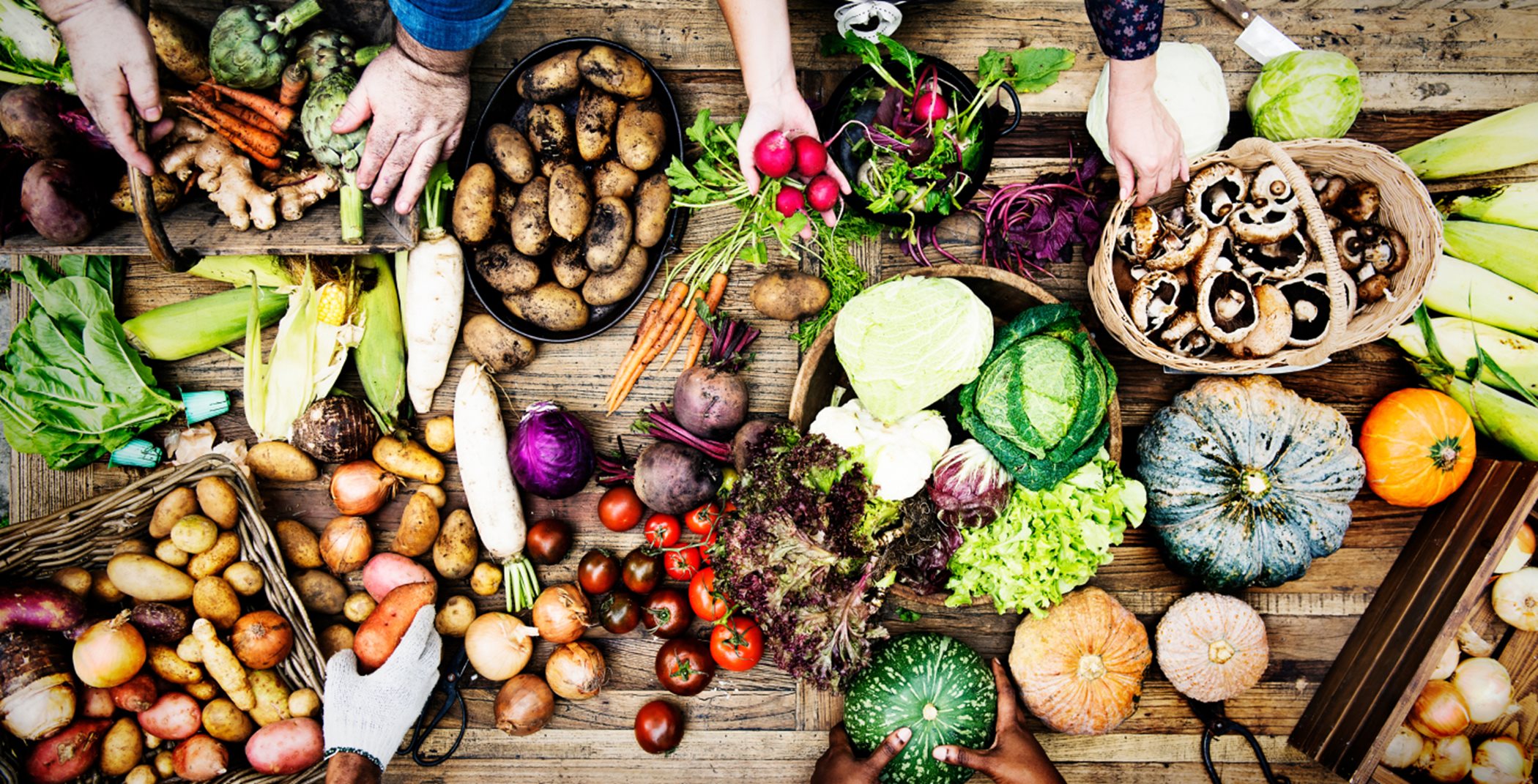 Overhead shot of people sharing fresh produce at a wooden table