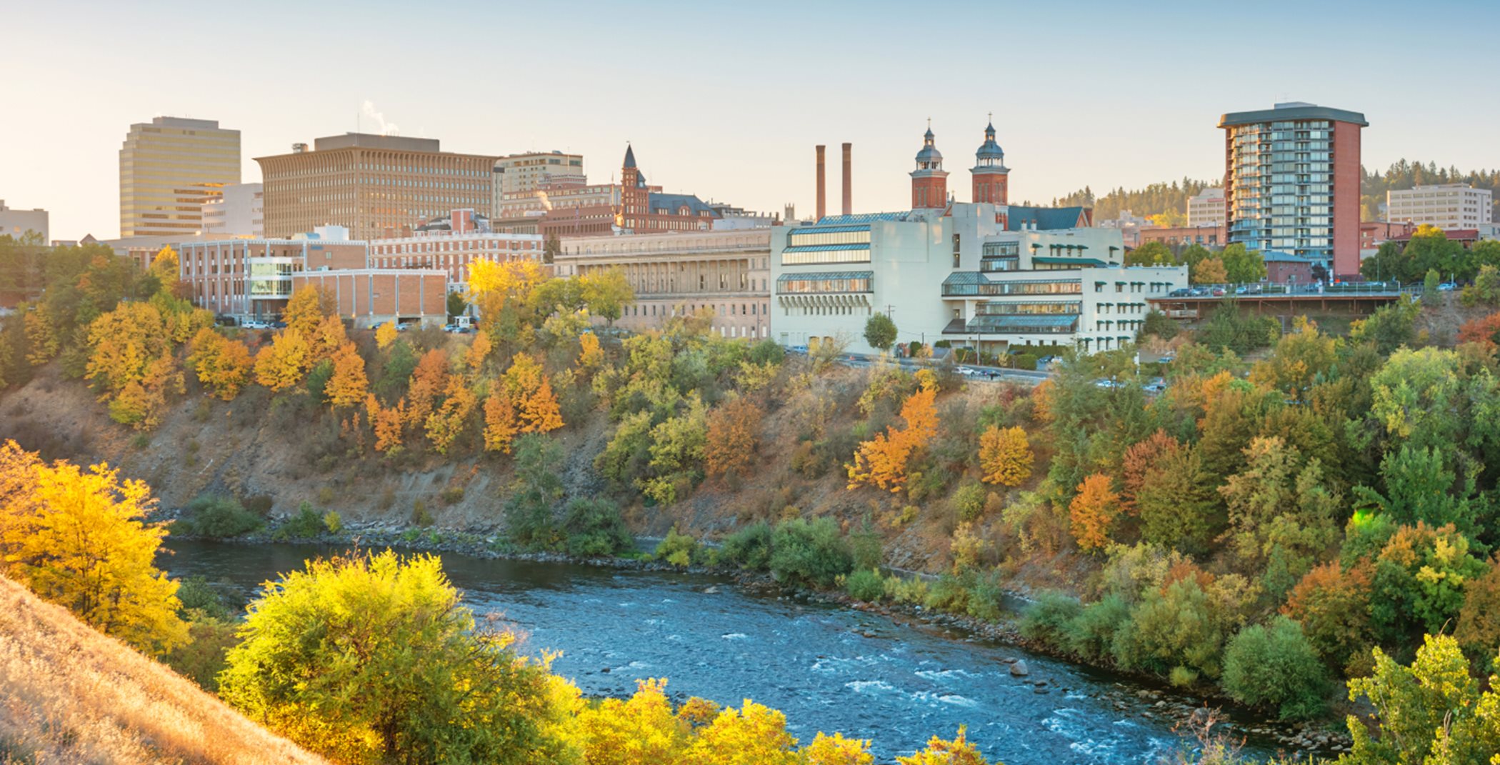 Spokane river surrounded by fall trees with a cityscape in the background