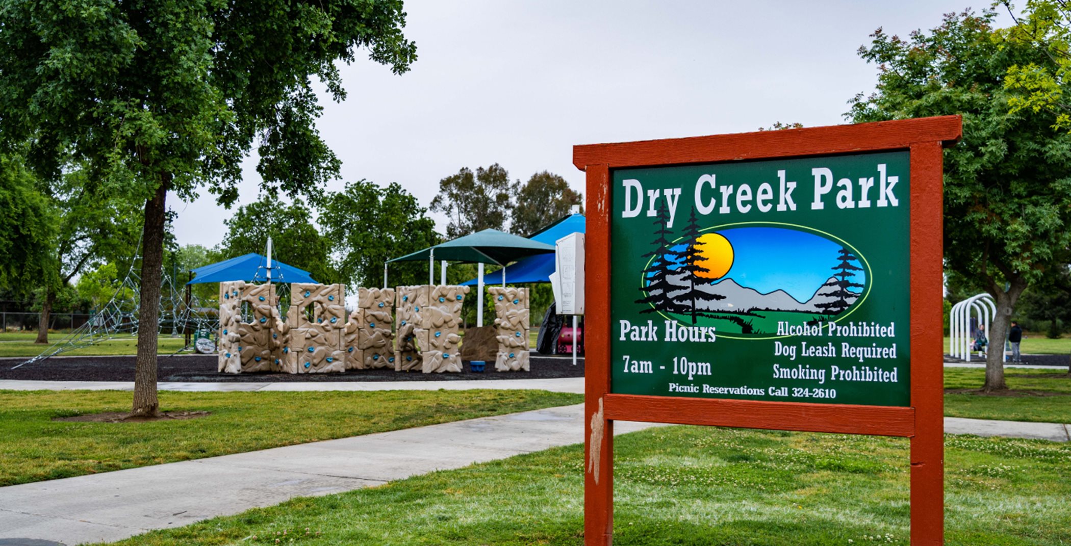Dry Creek Park entrance sign with rock climbing structure in the back 
