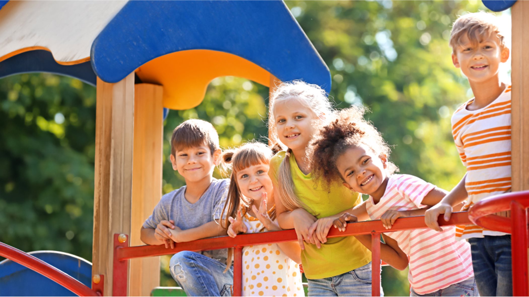Children on a play structure smiling at the camera
