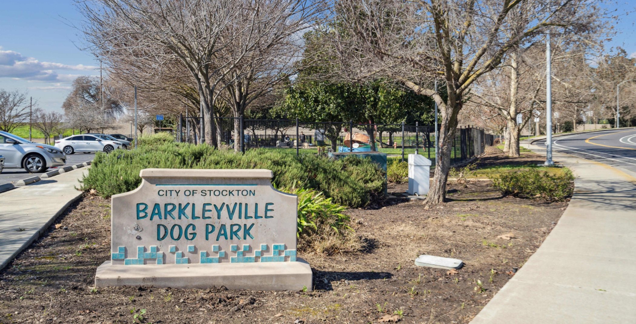 Dog park entry monument next to a paved pathway