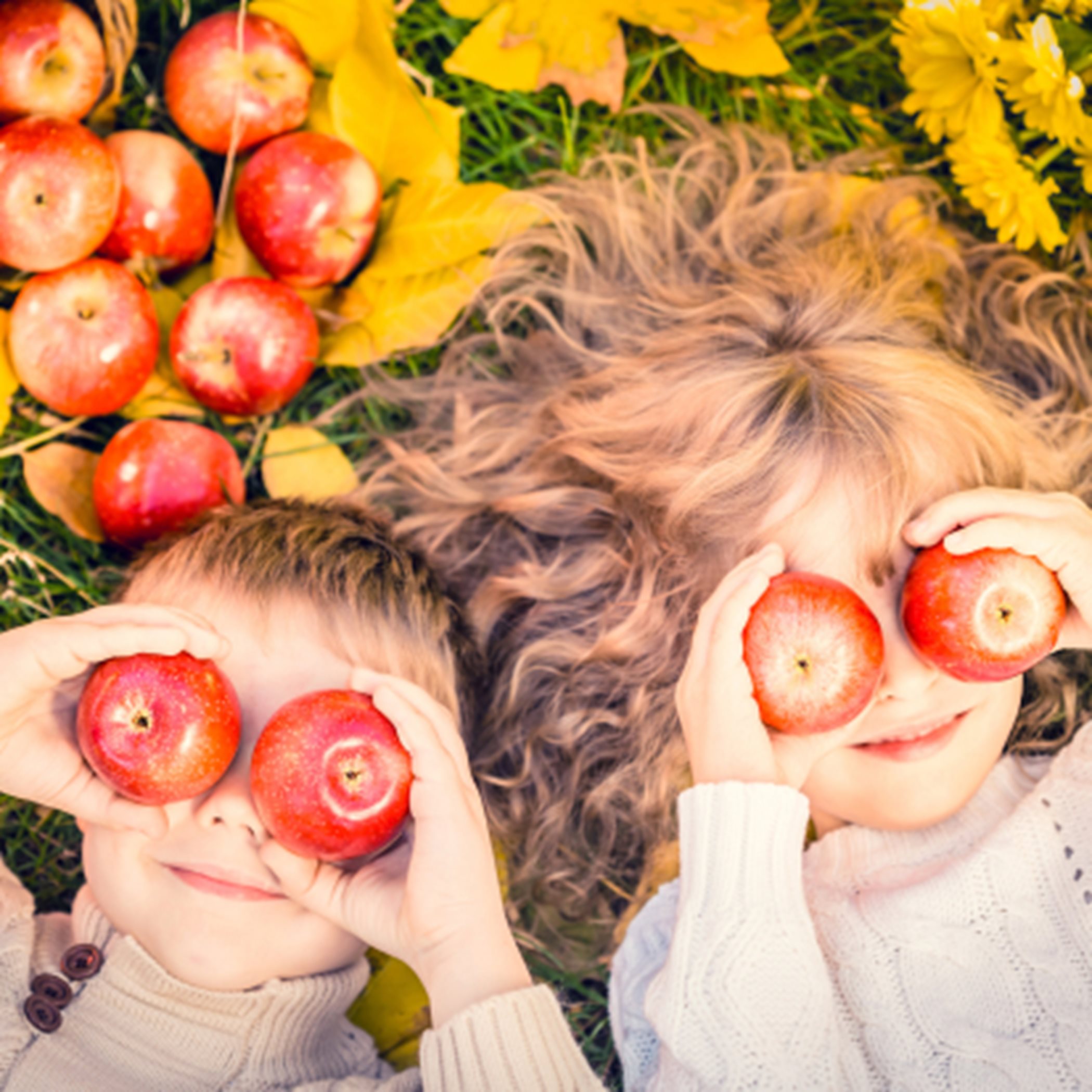 Kids playing with apples in leaves 