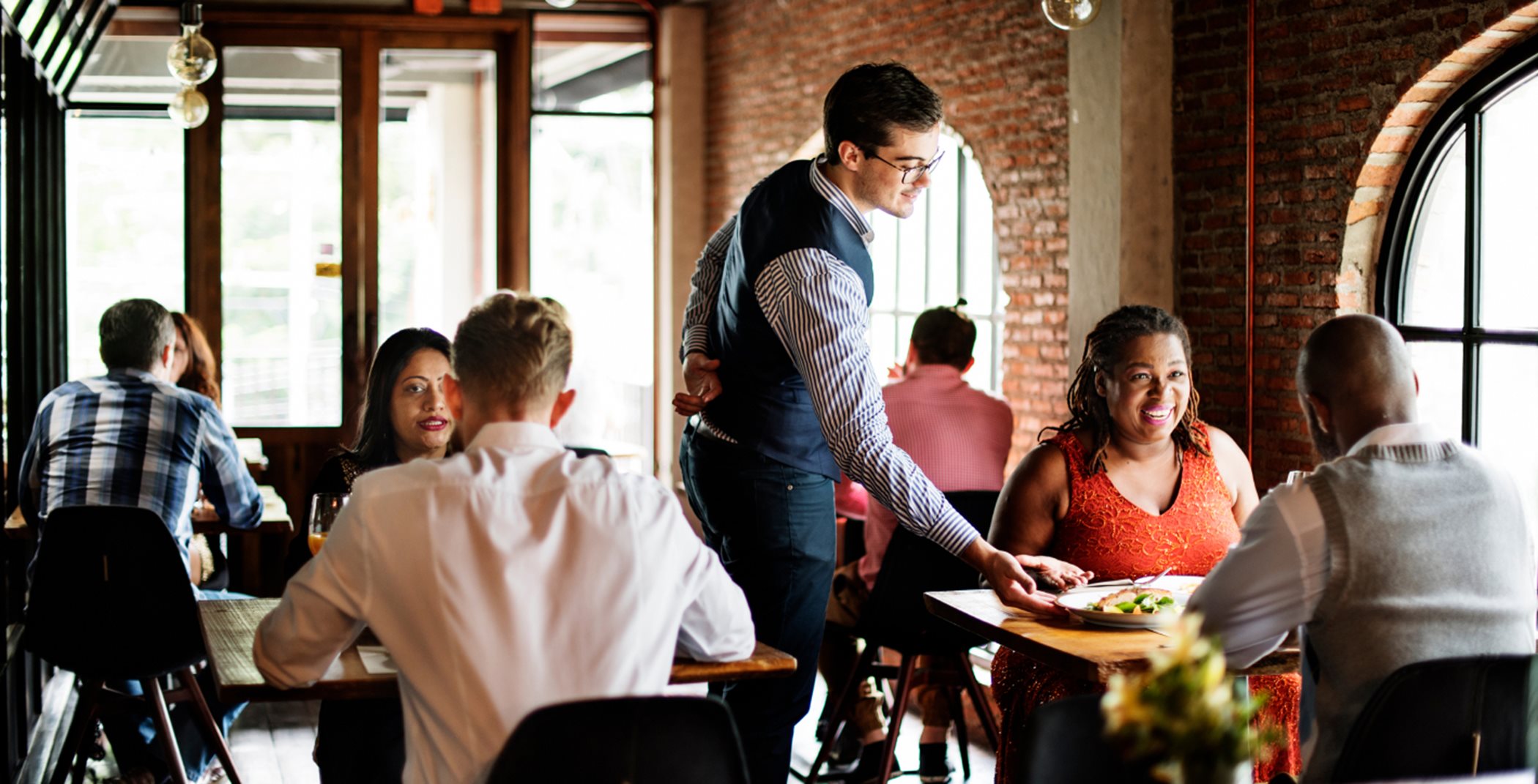 Server serving food to couple at restaurant