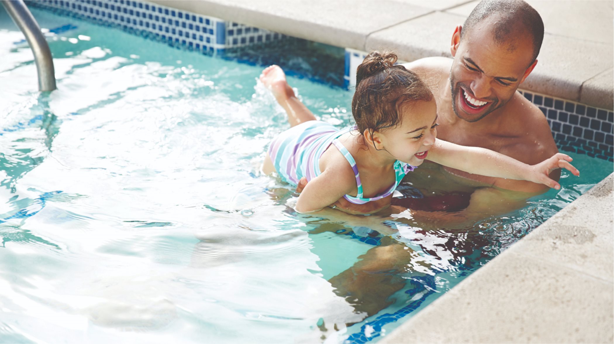 Father and daughter swimming in pool
