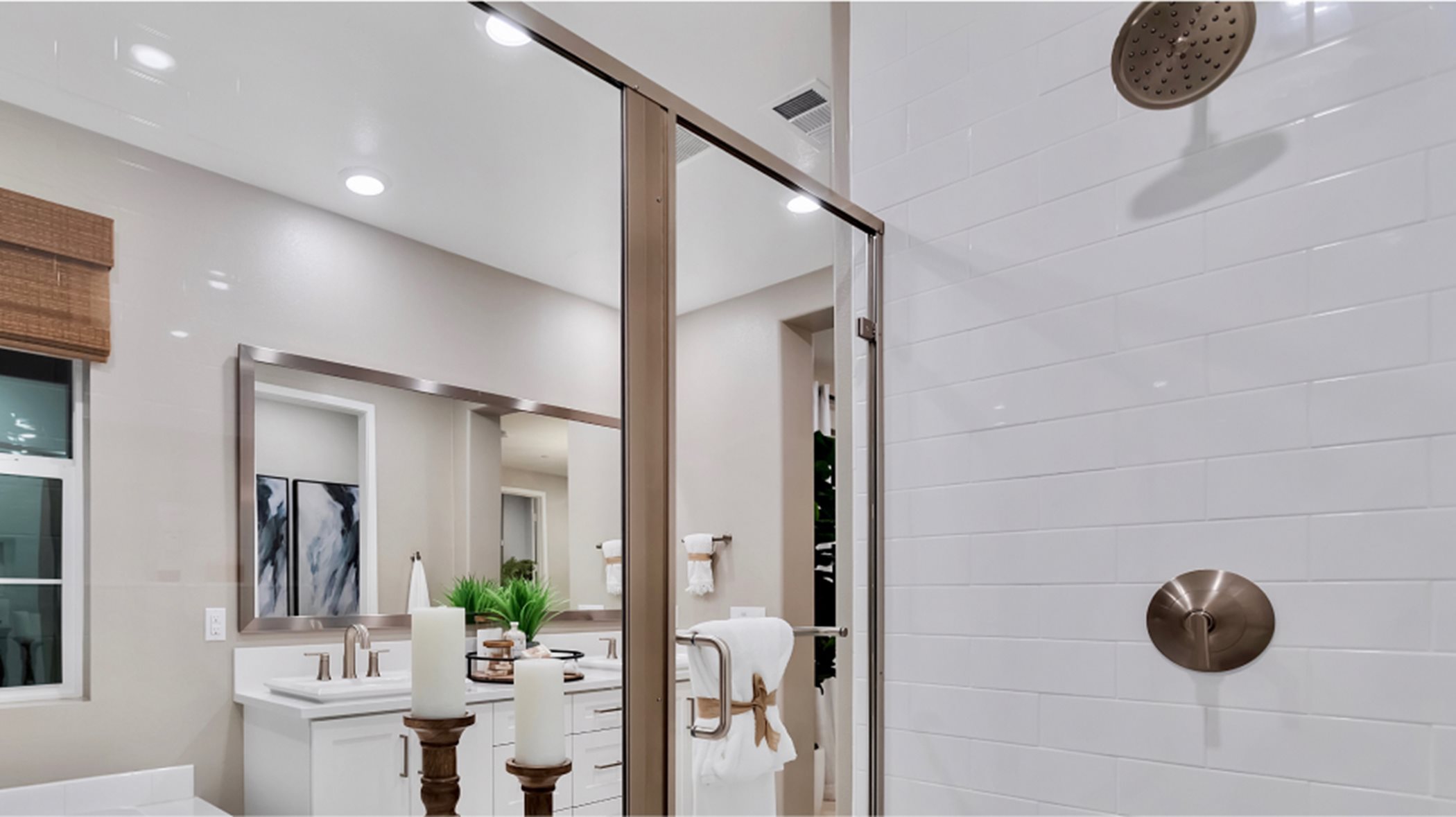 A glass-enclosed shower with a full-height ceramic tile surround and Moen® showerhead in the owner’s suite bathroom
