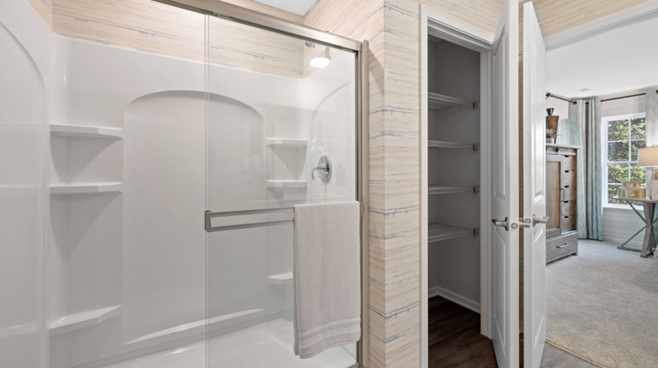 Darcy Fiberglass shower with clear glass door, brushed nickel trim and built-in shelving in owner's suite bathroom
