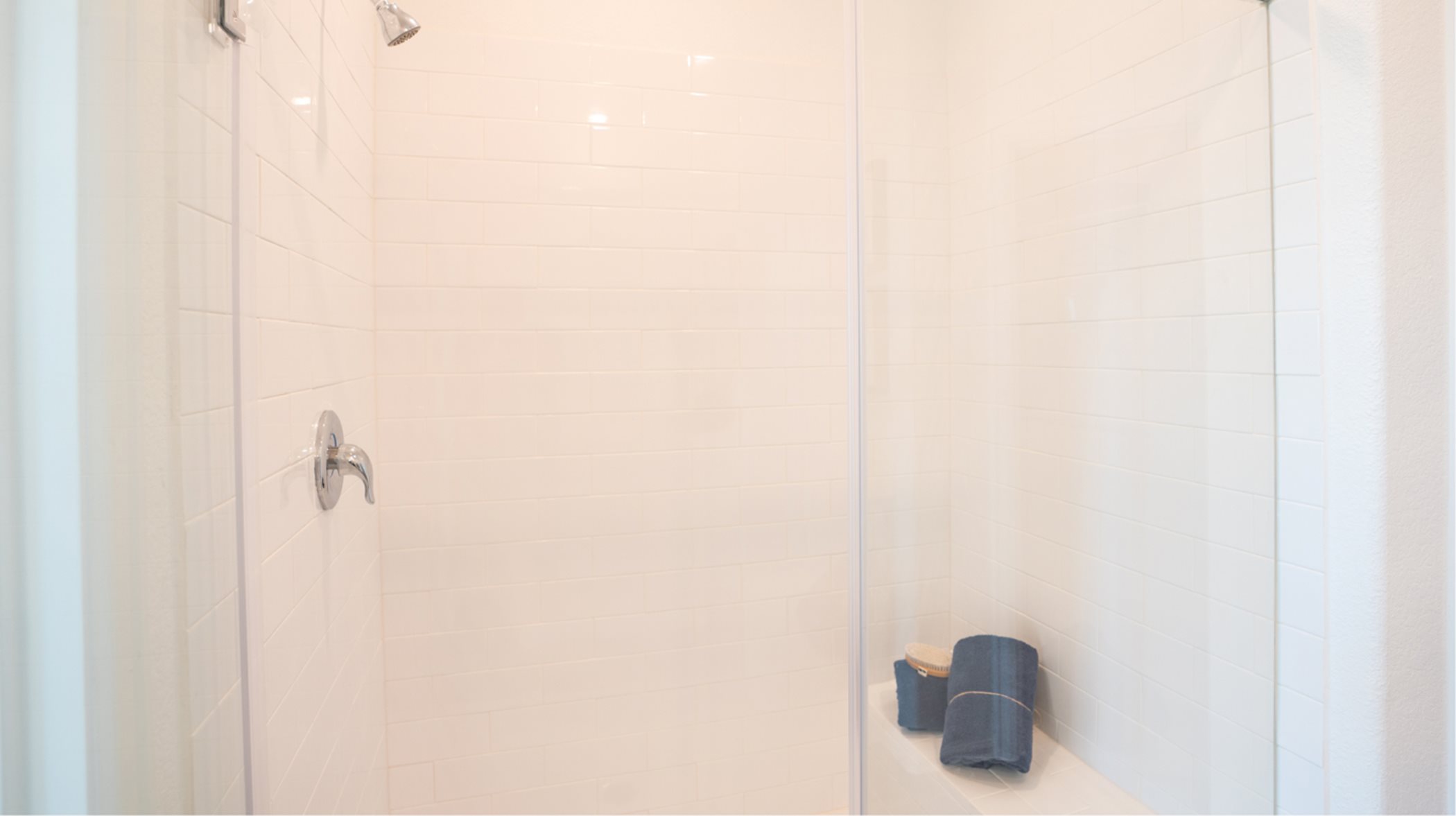 Shower with a built-in step or seat and tile surround and glass enclosure